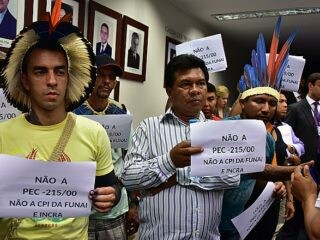 Manifestantes mostram cartazes contra a PEC 215 na CPI da Funai e do Incra, na terça-feira (24)