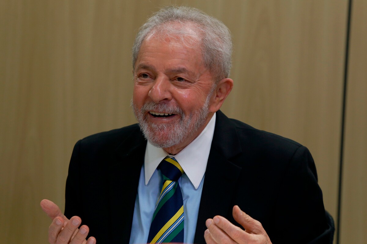 Ex-presidente Lula é um homem branco de 70 anos, com cabelos grisalhos e olhos castanhos; ele veste terno preto com camisa azul e gravata listrada