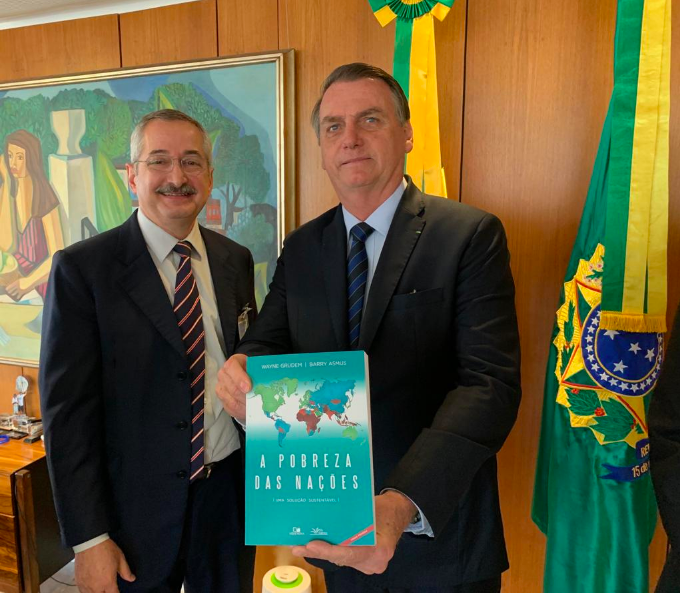 Antônio Cabrera ao lado do presidente Jair Bolsonaro em seu gabinete em Brasília mostrando um exemplar do livro "A Pobreza das Nações"