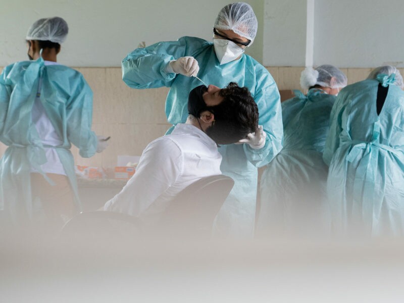 Em uma sala de uma unidade de saúde, enfermeiras aplicam teste de coronavírus em pacientes