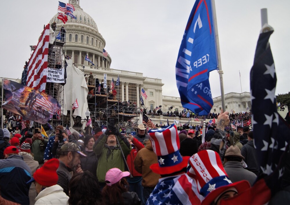 Imagem mostra dezenas de manifestantes em invasão ao Capitólio, EUA; todos vestem as cores da bandeira americana em chapéus, faixais e bandeiras