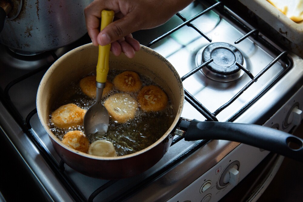 Imagem mostra as mãos de uma mulher fritando comida