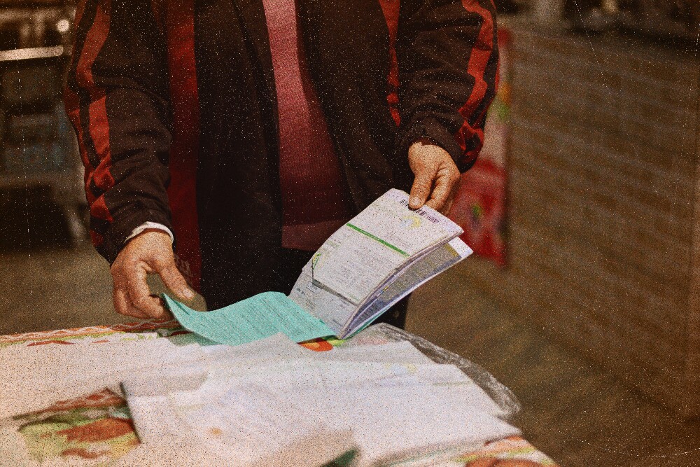 A imagem mostra as mãos de uma mulher folheando documentos, contratos e recibos