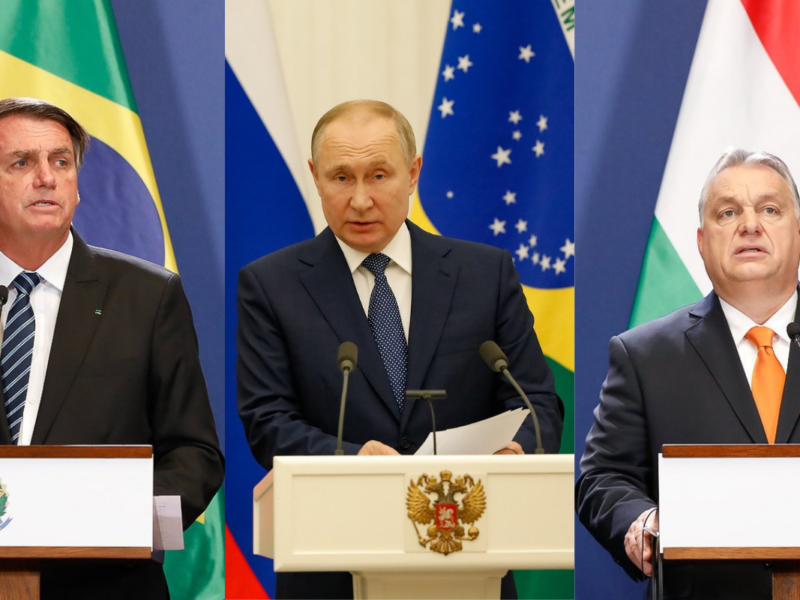 Da esquerda para a direita: Jair Bolsonaro, Putin e Orbán; ambos são homens brancos, eles vestem ternos e posam em cima de um palanque