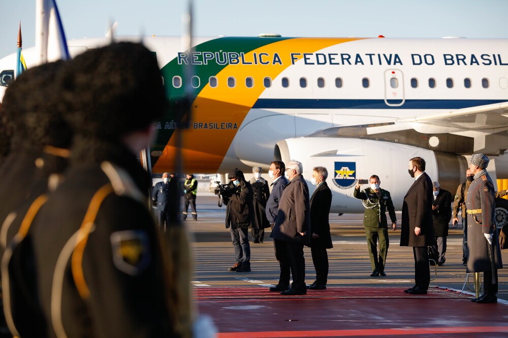 Bolsonaro posa ao lado do avião da Força Aérea Brasileira, com soldados russos a sua frente