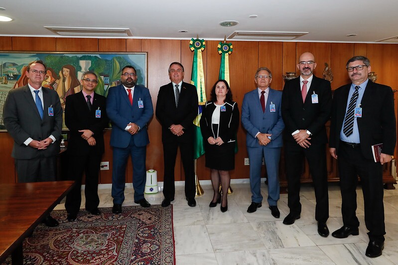 Presidente Bolsonaro posa ao meio entre oito homens e uma mulher, entre eles Uziel Santana; todos vestem roupas sociais