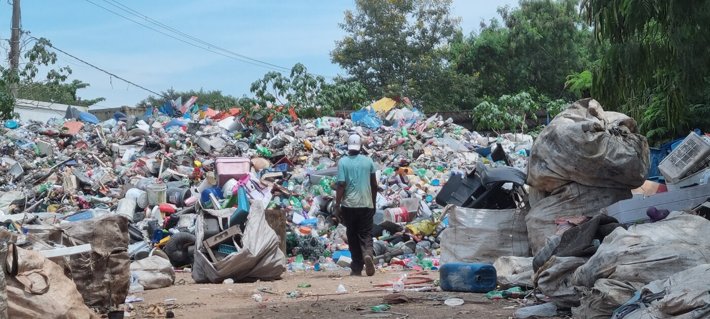 Imagem mostra montanha de lixo em aterro, com um trabalhador em meio aos descartes