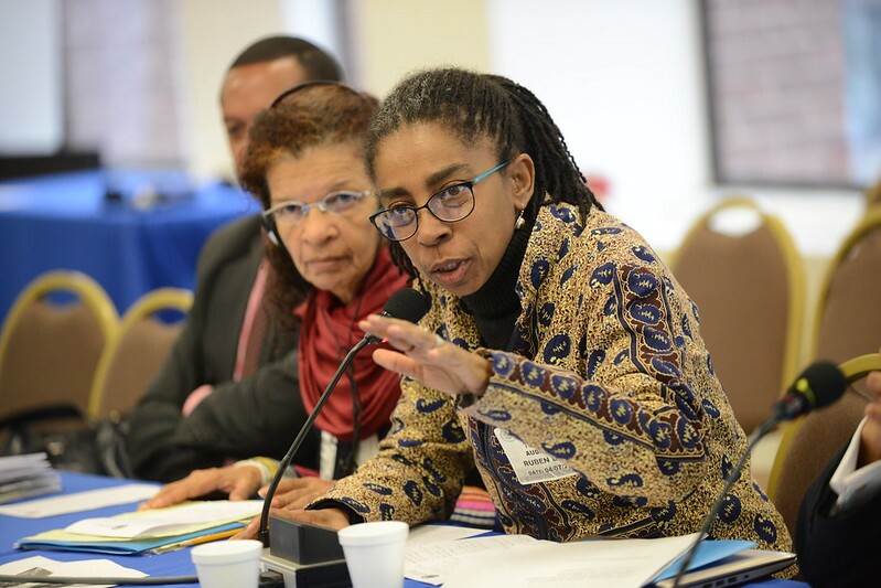 Jurema Werneck durante sessão da Comissão Interamericana de Direitos Humanos, em 2016; Jurema é uma mulher negra com cabelos e olhos castanhos, ela usa óculos quadrados e veste um casaco colorido