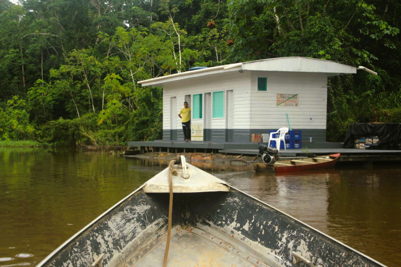 Imagem mostra entrada de Resex, com barco no rio e construção de madeira na margem