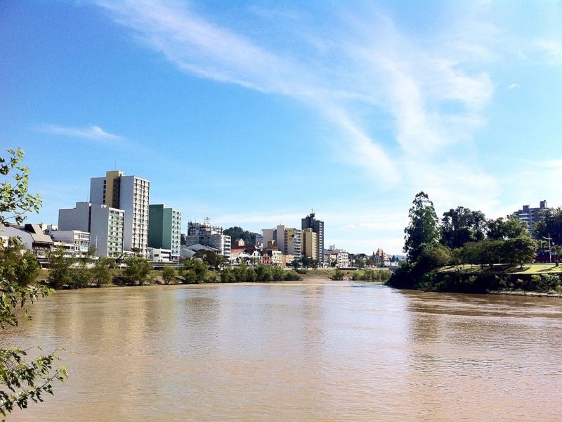 Imagem mostra trecho do rio Itajaí-Açu, em Santa Catarina, margeado por construções e mata ciliar