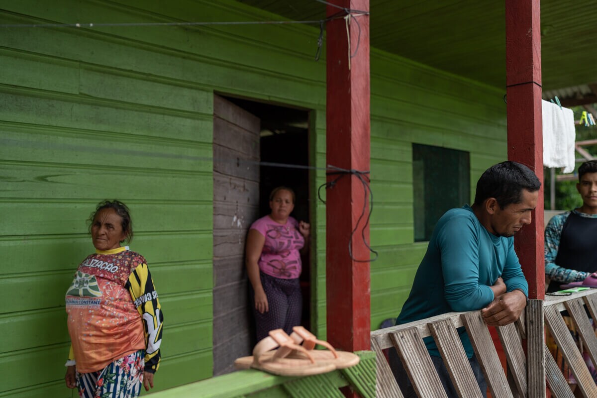 Mãe e irmãos de Amarildo da Costa Oliveira, o Pelado. Eles estão na varanda de uma casa de madeira pintada de verde