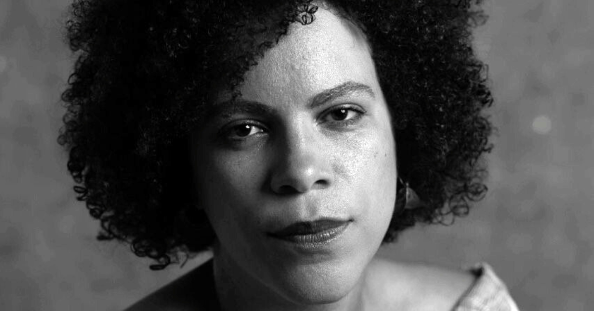 Ynaê Lopes dos Santos, é uma mulher negra com cabelos cacheados e olhos escuros.