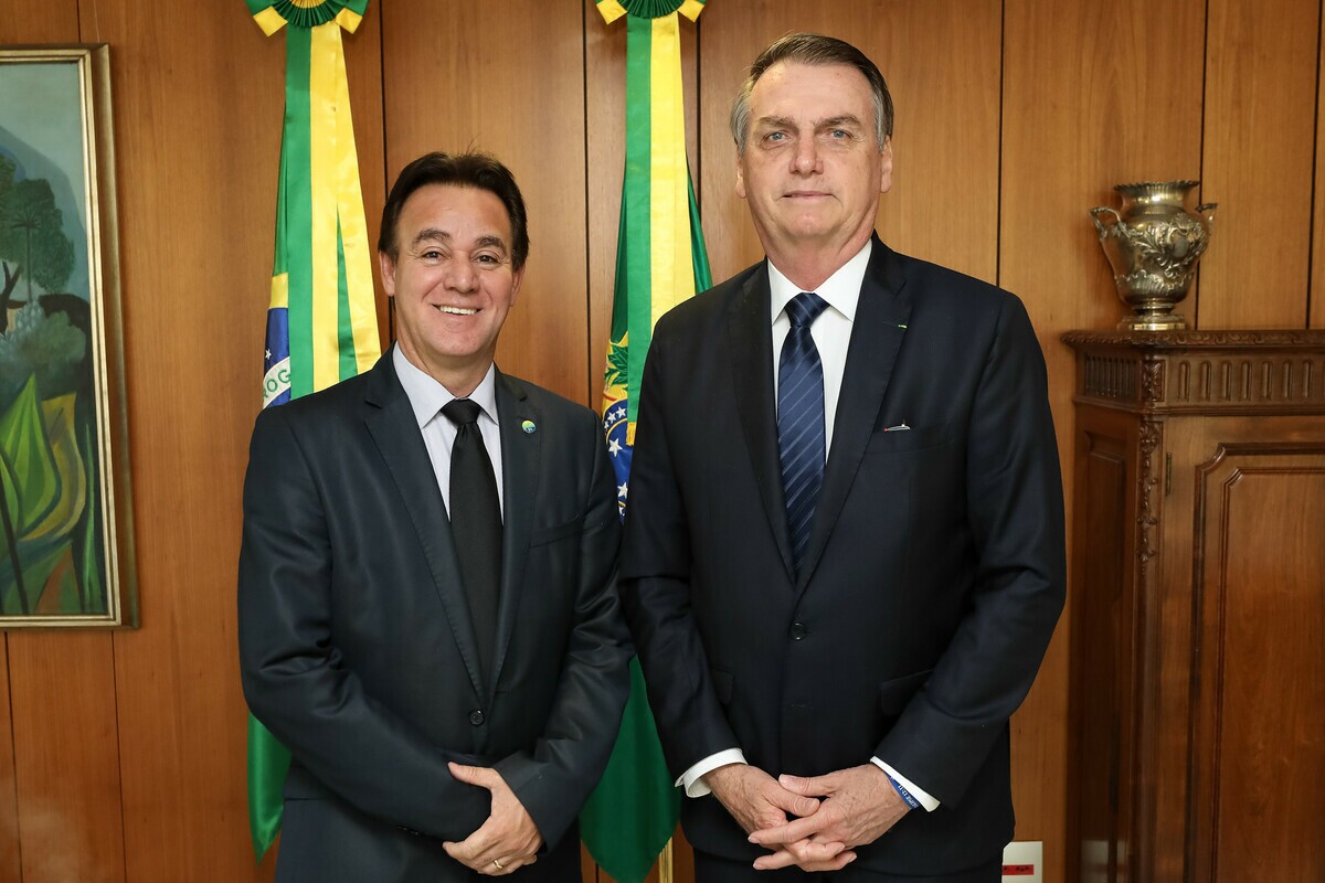 À esquerda Adilson, um homem branco com cabelos e olhos castanhos, ele usa terno e gravata pretos e à direita o presidente Jair Bolsonaro.