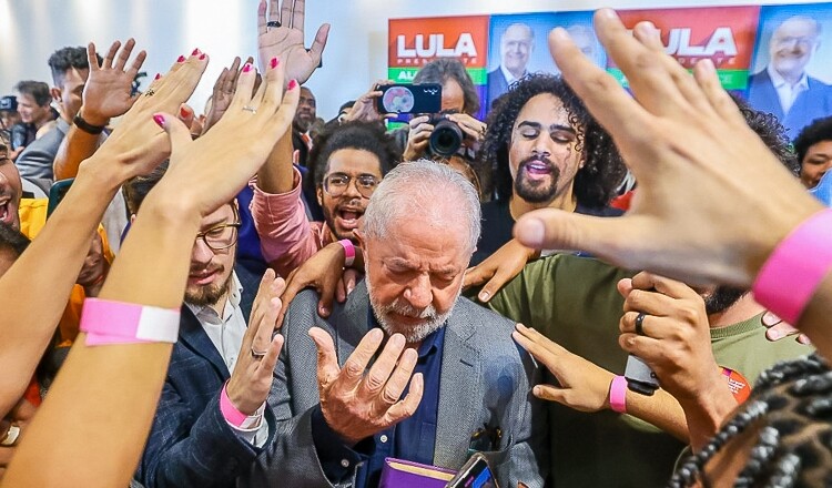 Na imagem, o candidato a presidência Lula recebe uma oração de seus eleitores.