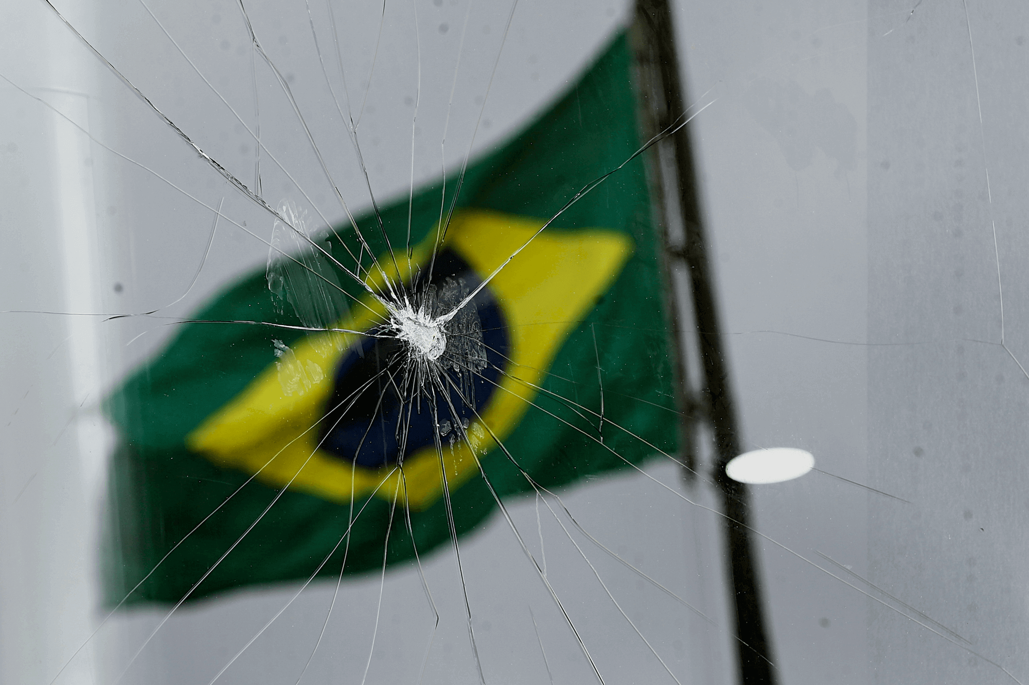 Reflexo da bandeira do Brasil em vidro quebrado em janela do Congresso, em Brasília, após atos golpistas