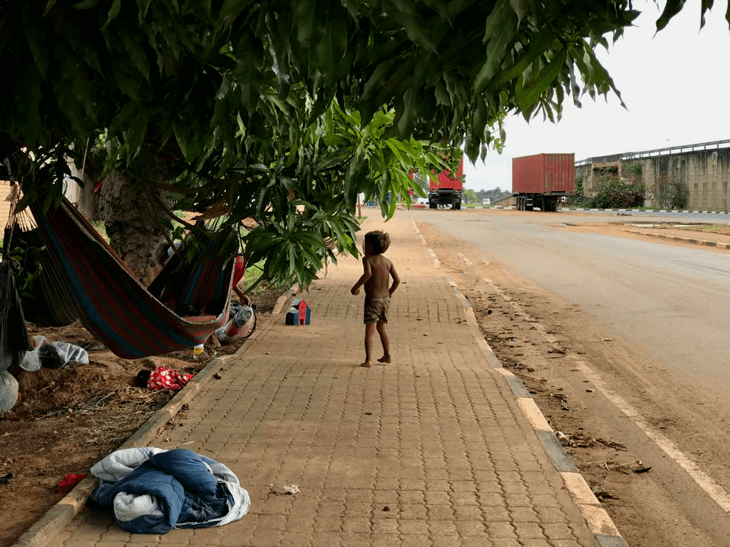 Criança yanomami andando em calçada à margem de estrada em Boa Vista (RR)