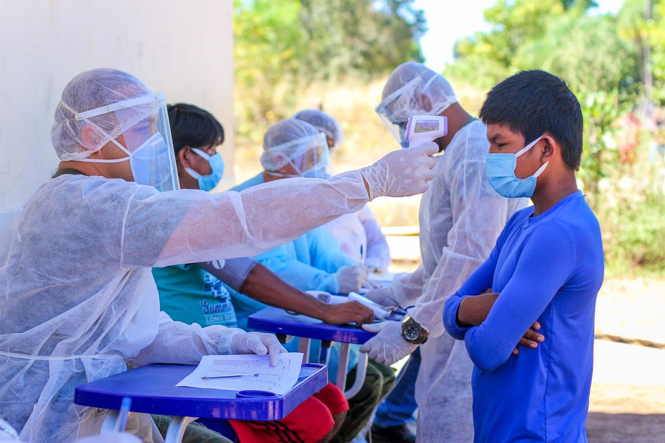 Equipe médica atende indígena durante pandemia de coronavírus. Na foto, é possível ver profissional medindo a temperatura de uma criança.