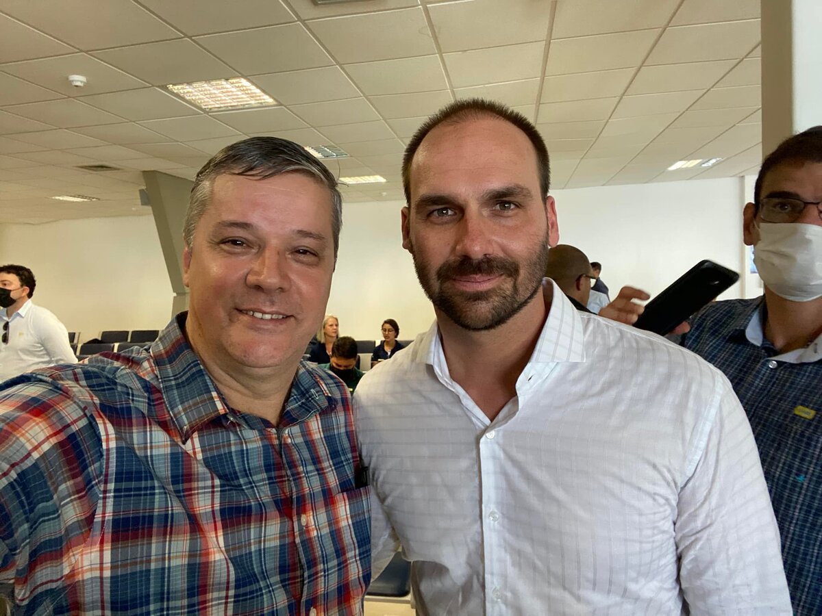 À esquerda, Paulo Generoso usando camisa xadrez, e à direita, Eduardo Bolsonaro usando camisa branca.