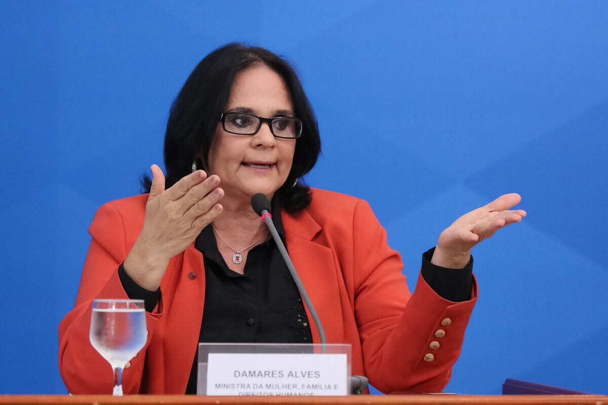 Atual Senadora e Ex-Ministra da Mulher, Família e Direitos Humanos, Damares Alves gesticula enquanto fala ao microfone.