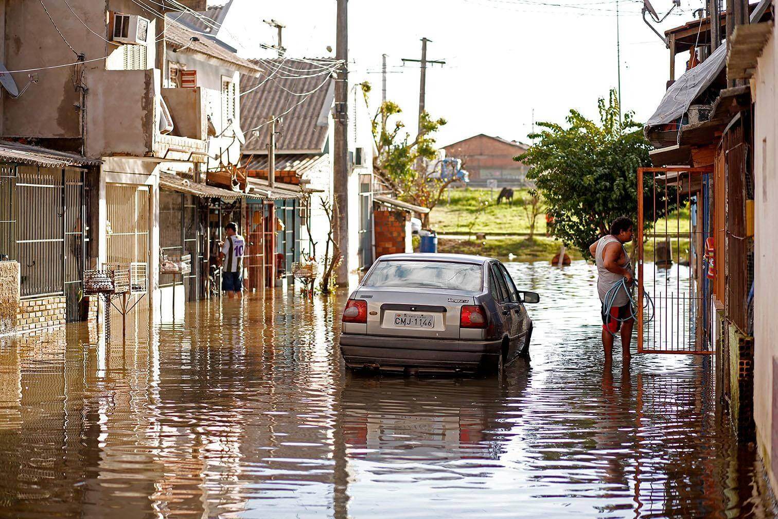 Carro anda em rua alagada em Porto Alegre durante período de chuvas intensas