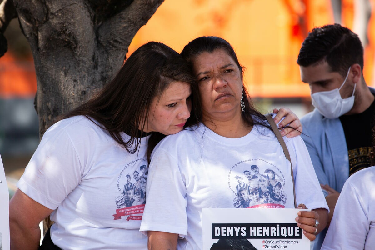 Na imagem, Maria Cristina Quirino Portugal, uma mulher de 43 anos, branca, com cabelos e olhos pretos. Maria Cristina está sendo amparada. Maria Cristina usa uma camiseta com o rosto das vítimas do massacre de Paraisópolis.