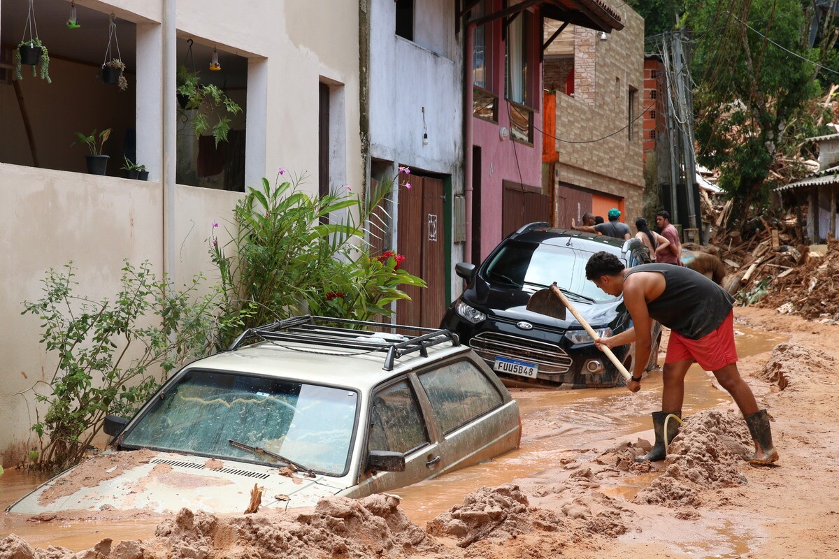 Moradores de Barra do Sahy retiram a lama após deslizamentos em fevereiro.