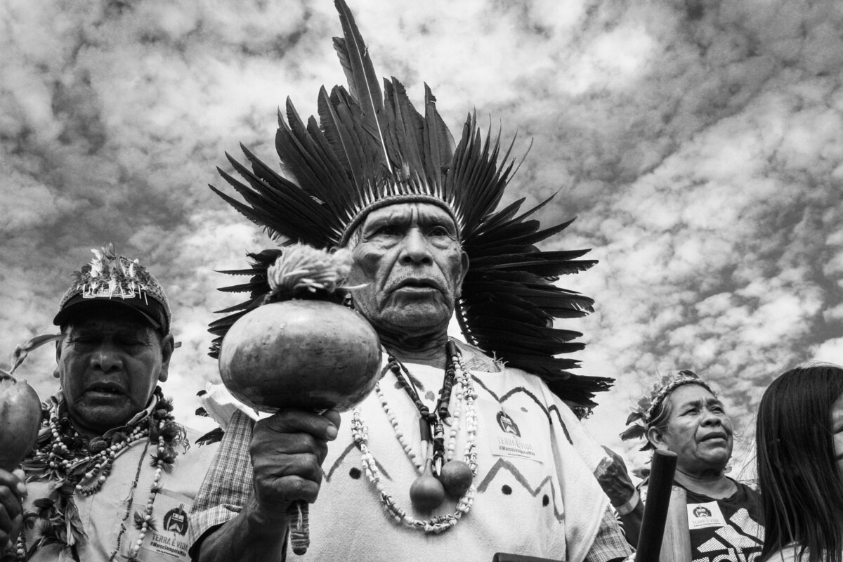 Homens indígenas usam trajes típicos em protesto.