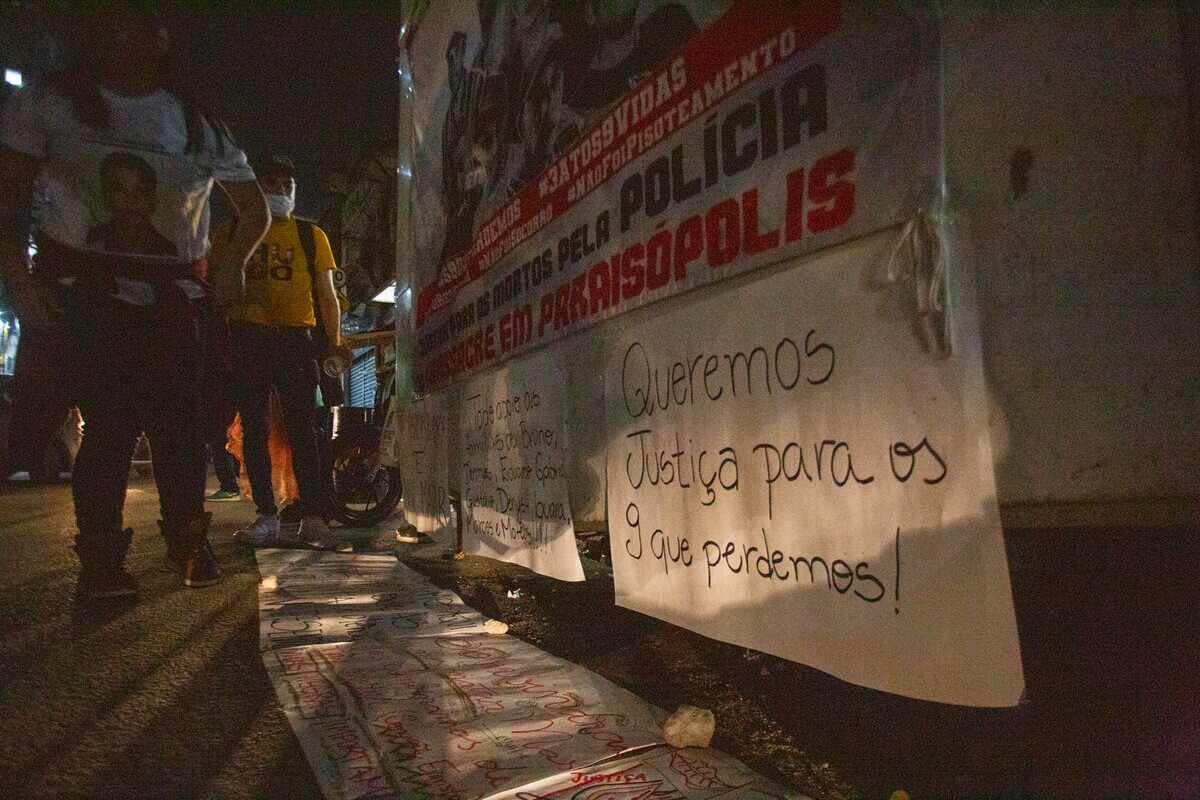 Cartaz com a frase "queremos justiça para os 9 que perdemos" colado em parede