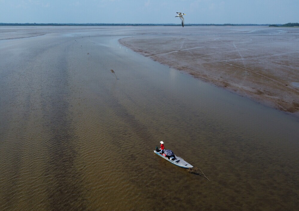 Barco navega no rio Solimões durante seca do rio
