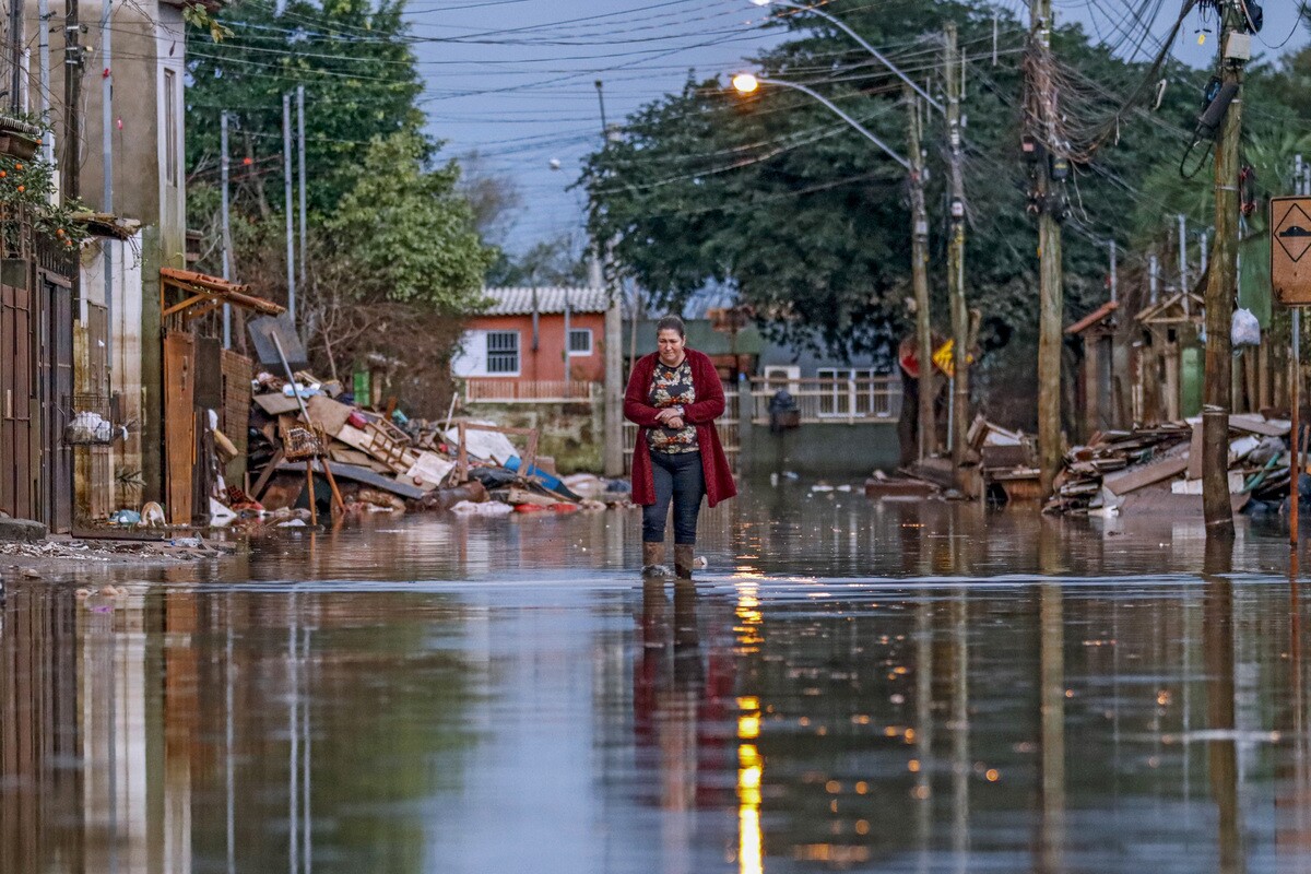 Porto Alegre (RS), 19/06/2024 - Moradora do Rio Grande do Sul anda em rua alagada na Vila da Paz durante o desastre climático de 2024