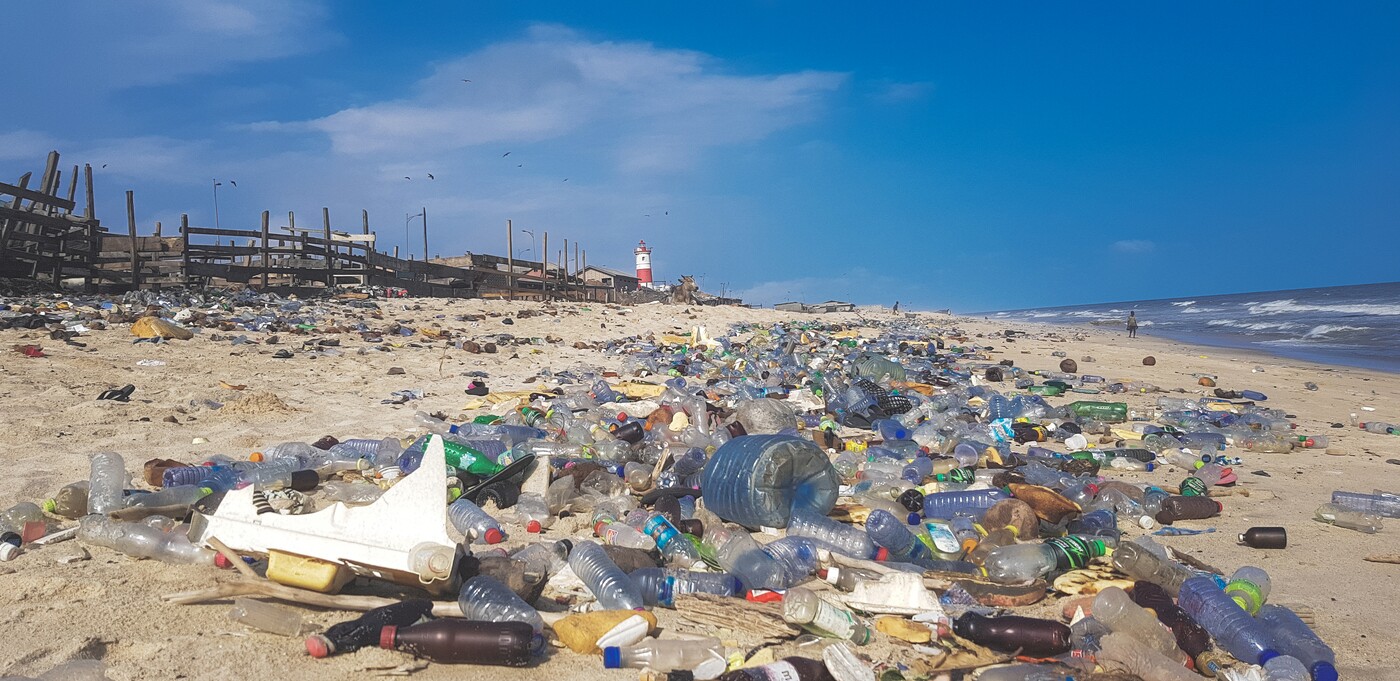 Foto mostra areia de praia coberta por poluição de materiais plásticos