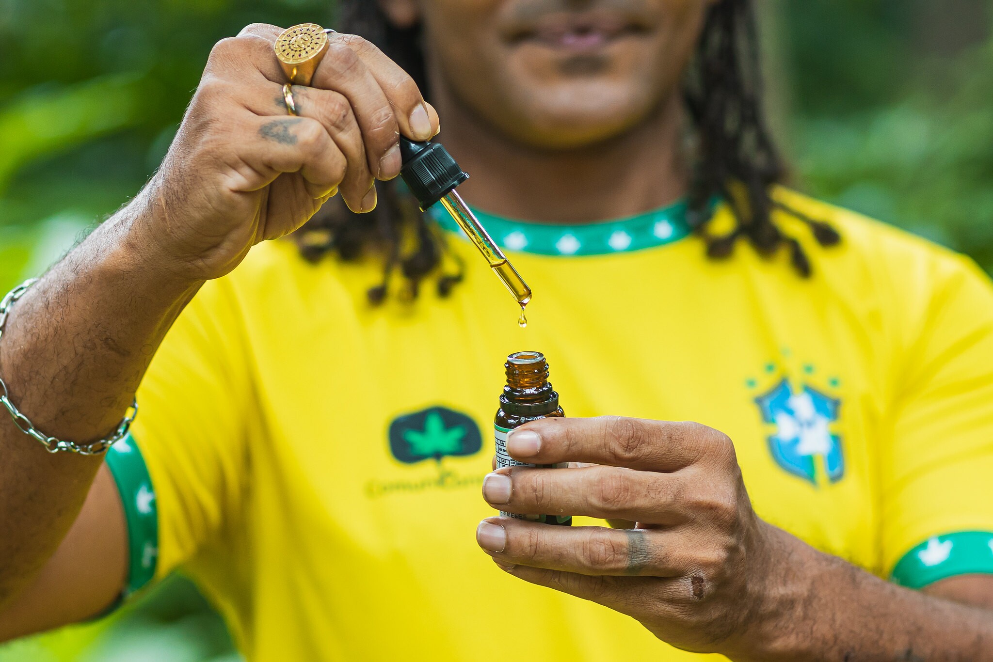 Imagem mostra o jornalista Luan Cândido segurando óleo medicional feito à base de maconha