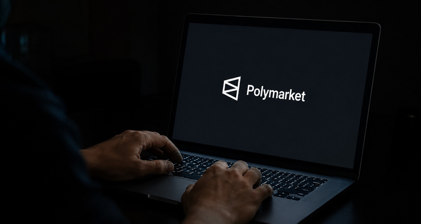 Em uma sala escura, mãos de uma pessoa digitam em um notebook cuja tela exibe apenas o logotipo da Polymarket